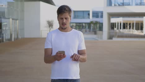 Relaxed-young-man-using-smartphone-during-stroll.